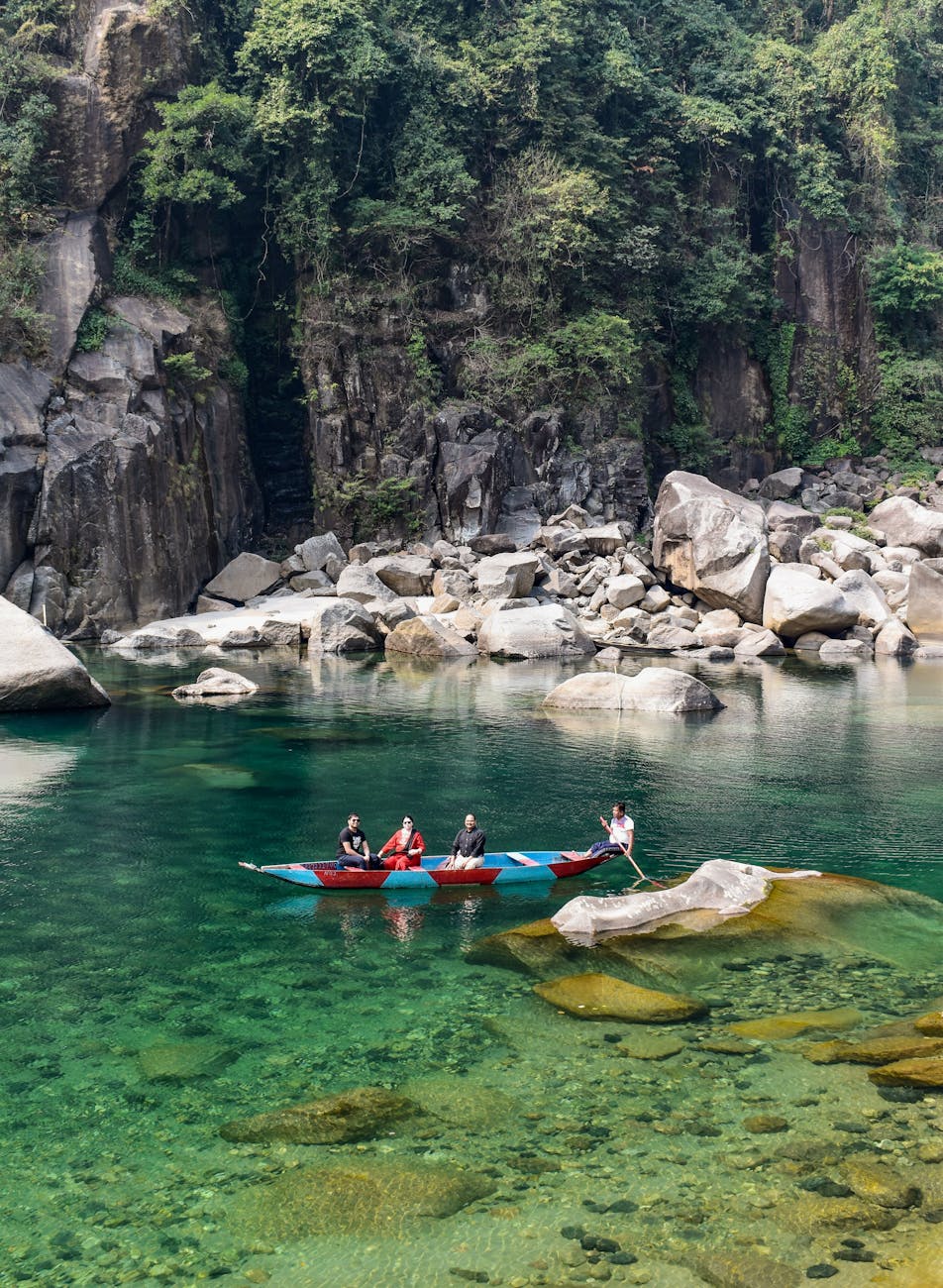 people riding a boat on the river near the rock formation
